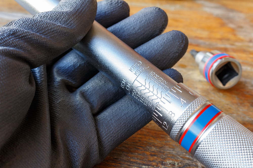 Mechanic's hand in the working glove holds the torque wrench.